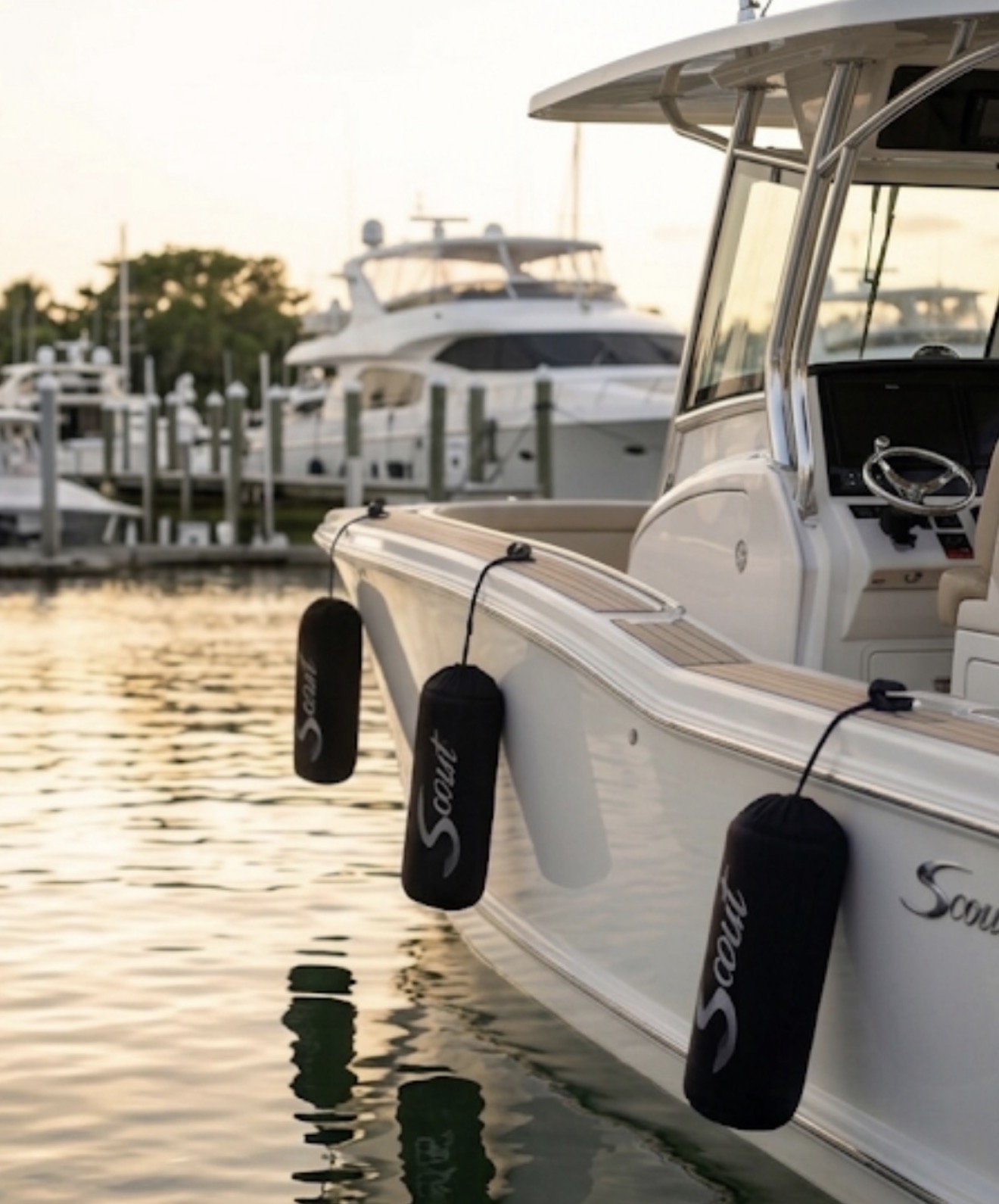 Scout Boats custom black FenderSox at golden hour — three fenders hanging off the hull at sunset